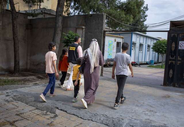 Eine Gruppe von Menschen geht durch einen offenen Hof.